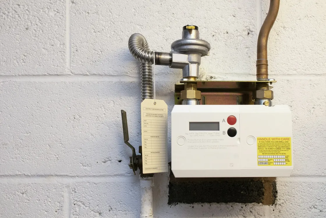 Residential natural gas meter and regulator on a painted block wall