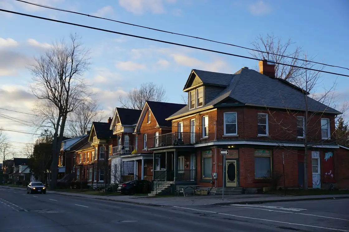 Row of older red brick houses on a street corner under a clear sky