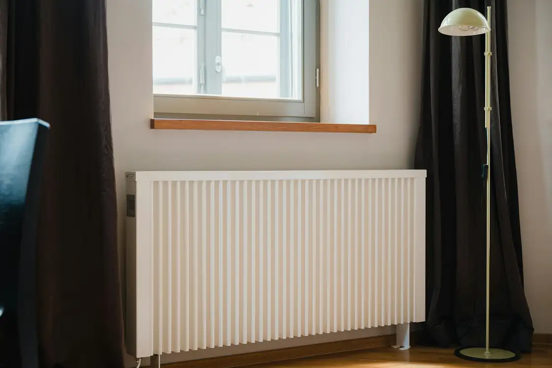 White panel radiator under a window in a bright room
