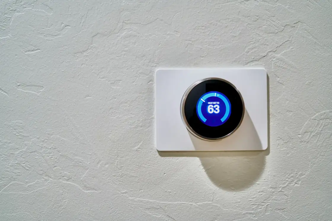 Round smart thermostat mounted on a textured white wall
