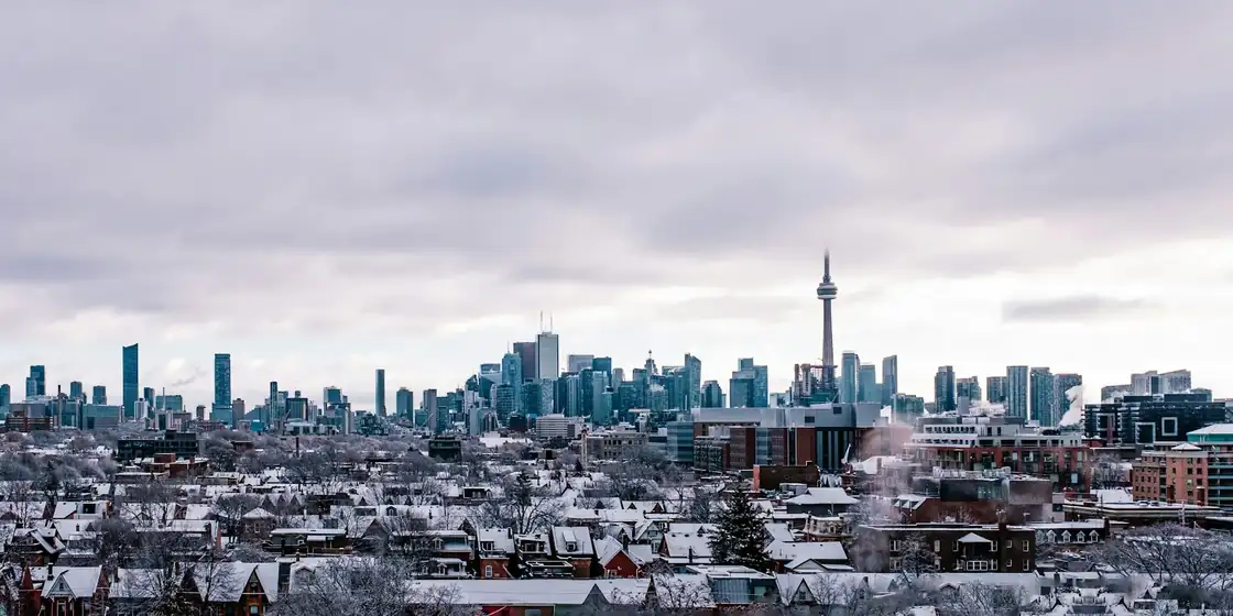 Toronto skyline with the CN Tower above snowy residential rooftops